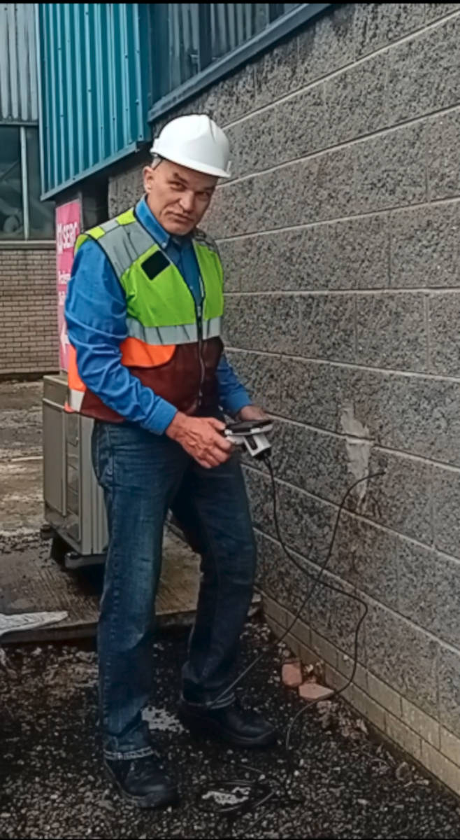 Marcin Piotrowicz inspecting a cavity wall with a boroscope in safety gear.